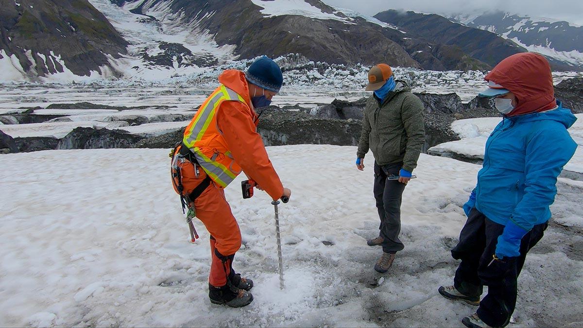三个人用螺旋钻钻透纳冰川