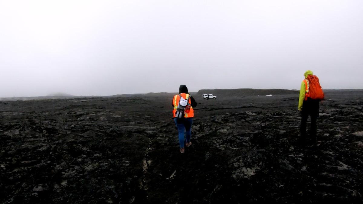 研究人员走过黑色的冰岛熔岩流.